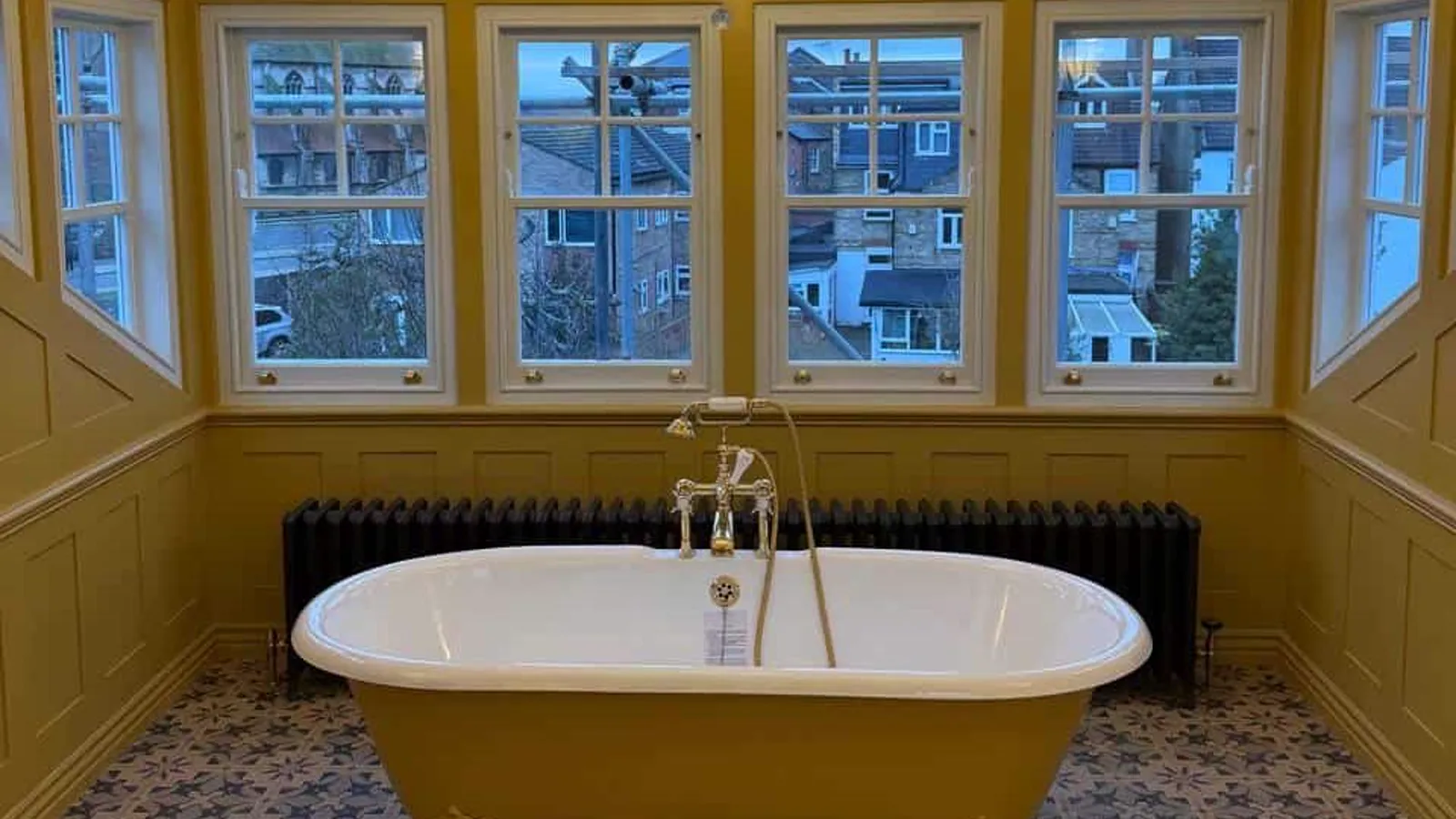 A period bathroom with a yellow roll-top bath and a crystal chandelier